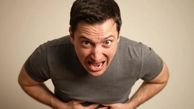 Close-up man with hilarious face holding stomach like resisting to poop
