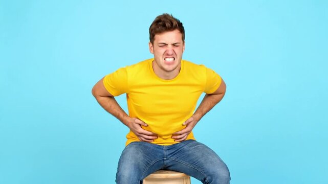 Young man with exaggerated funny face pressing stomach as if resisting poop
