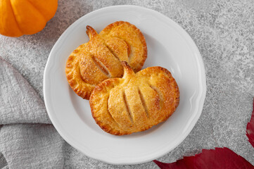 Pumpkin mini pies or hand pies with glass of coffee on a stone background. Traditional autumn dessert for Halloween and Thanksgiving. Copy space