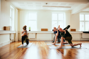 Yoga teacher leading male students in a class. They are doing a yoga pose, with their hands folded in front of them