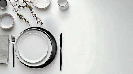 Elegant white table setting with black rimmed plate and delicate greenery overhead view