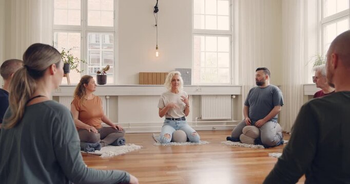 Yoga teacher talking with a mixed age range
group of students before a beginners yoga
class