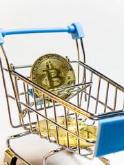 A shopping cart is filled with gold coins and a Bitcoin coin.  Russia. Moscow. 10.09.25