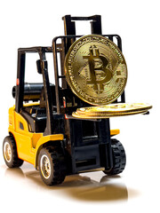 A yellow loader lifts a large gold bitcoin.