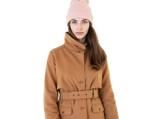 Fashionable young woman in stylish brown coat with pink beanie stands against a white background during an indoor photoshoot