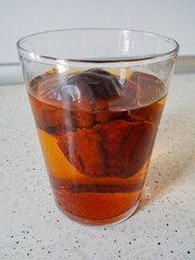 Sun-dried Mediterranean tomatoes soaking in a glass bowl of water on a light countertop.