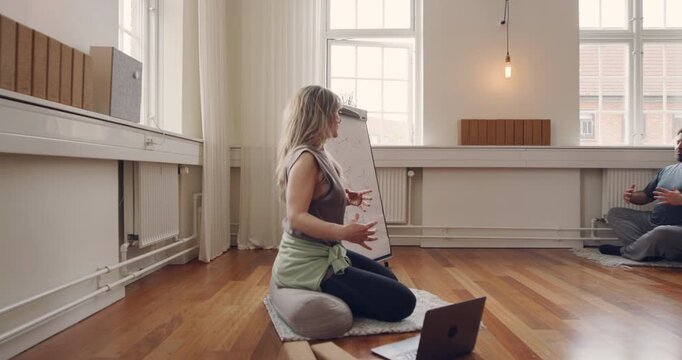 Yoga instructor leading a diverse group of
students through breathing exercises during a
beginners yoga class