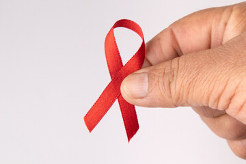 fingers holding red ribbon for World AIDS Day