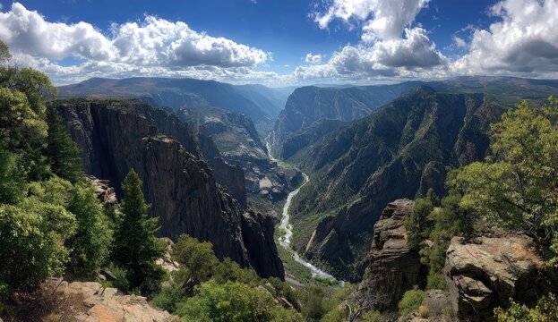 High-angle view of a dramatic canyon, river winding through steep, dark rock walls, with lush greenery on the rim. Sunny day with fluffy clouds