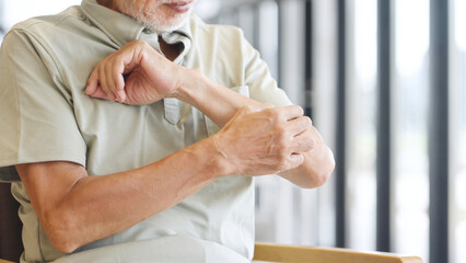 皮膚の疾患で腕を掻くアジア人高齢者