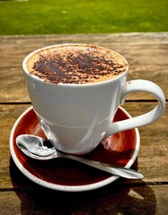 Cup of Hot Cappuccino with Cocoa Powder on a Wooden Table