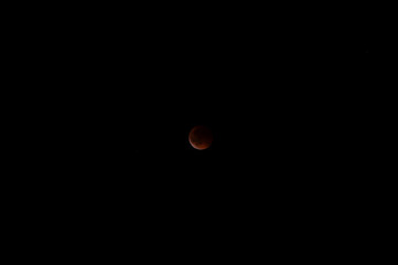 Munich, Germany - September 7th 2025: Total lunar eclipse (blood moon) with red-tinged lunar surface and bright crescent emerging against a dark night sky above Munich.