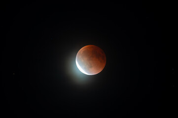 Munich, Germany - September 7th 2025: Total lunar eclipse (blood moon) with red-tinged lunar surface and bright crescent emerging against a dark night sky above Munich.