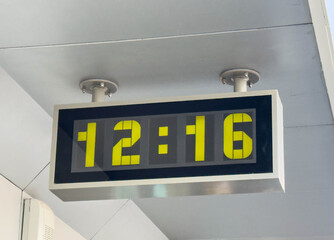 Modern digital clock displaying 12:16 in urban setting