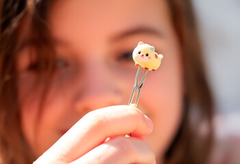 Child Holding a Kawaii Animal Paperclip: Focus on Miniature Charm