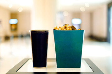 Beverage cup and popcorn container on a white surface