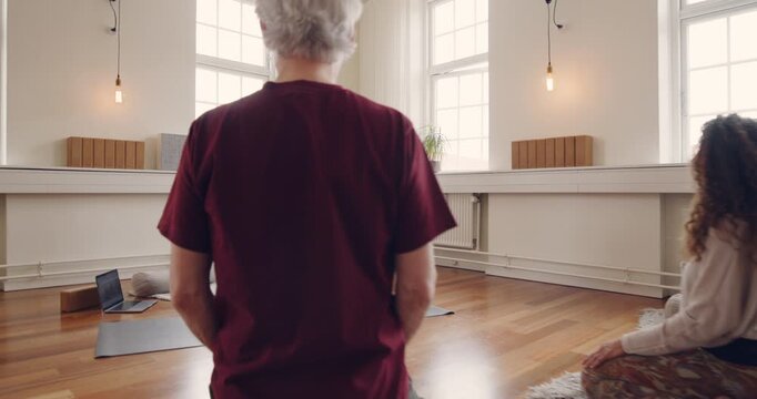 Yoga teacher using a mature student to show
her beginners class how to do yoga