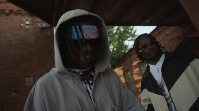 Two African American guys wearing y2k streetstyle outfits vibing to hip-hop music outdoors