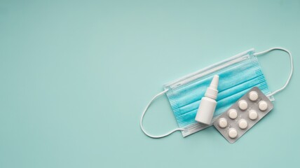 Medical Essentials: A surgical mask, nasal spray and blister pack tablets are neatly arranged, representing protection and care for health. A clean, clinical view of wellness and medical precautions.