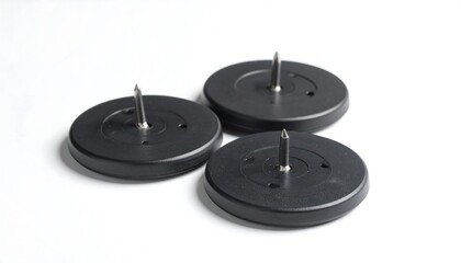 Three circular, black plastic adhesive pads, each with a centered metal pin, are displayed on a plain white background.