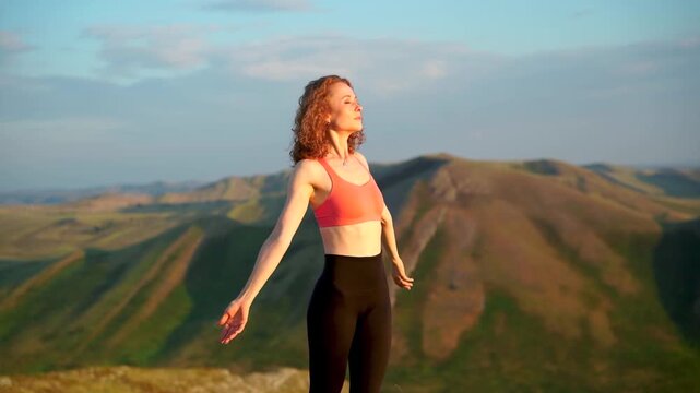 A woman practices yoga on a mat atop a mountain