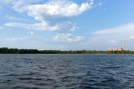 Wide lake view with trees, clouds, and a distant power plant