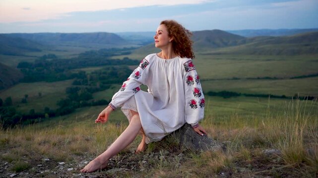 A woman in a national traditional dress on the background of hills