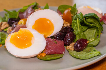 Boiled eggs with spinach, nuts, tomatoes, cheese, seasoned with pepper and salt and drizzled with olive oil.