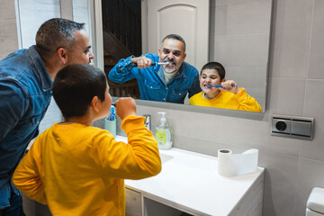 Father teaching oral hygiene to his son, brushing teeth together in the bathroom, promoting family bonding and healthy habits