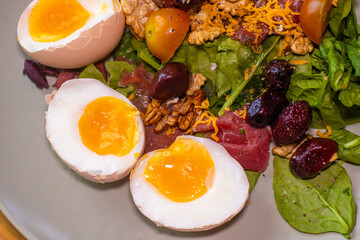 Boiled eggs with spinach, nuts, tomatoes, cheese, seasoned with pepper and salt and drizzled with olive oil.