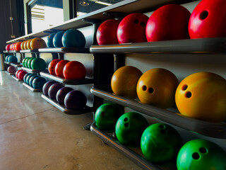 Close up view of colorful bowling balls on the rack, ready for players to choose. Concept of leisure activities, indoor sports, and fun moments at the bowling alley