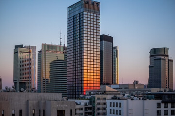 Fototapeta premium Warsaw, Poland, Skyscraper reflecting sunset hues, surrounded by modern urban architecture, showcasing glass facades and vibrant city lights, embodying contemporary urbanism and architectural beauty