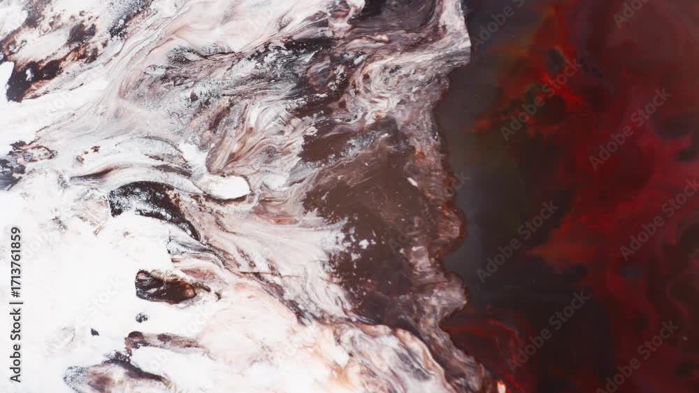 Poster blowing white and brown inks towards the red color to create abstract background.