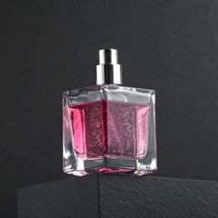 Pink perfume bottle on dark stone