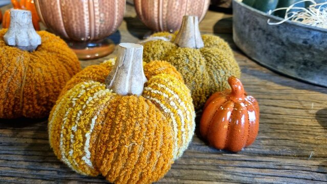 Fabric textile orange pumpkins and ceramic pumpa on a wooden table with decor, close-up, concept of a postcard for autumn and October holidays