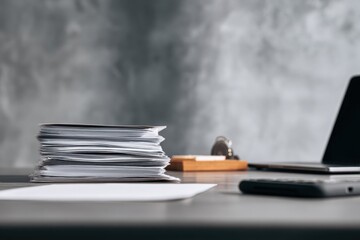 close-up of a desk in an office with documents, a laptop, and a phone on it, against a gray background, minimalistic style.