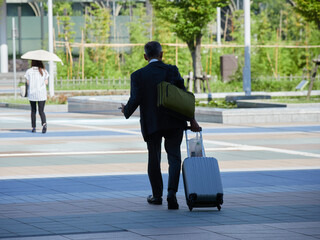 夏の朝の金沢駅西広場を渡る通勤中の会社員の姿