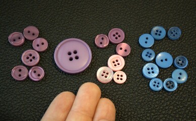 Creative composition of the number 2026 arranged from colorful buttons on a solid black background...