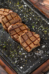 Grilled beef filet lokum served with herbs on black stone plate