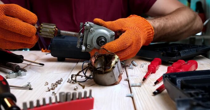 Repair of power tools. A master in a repair shop repairs a power tool