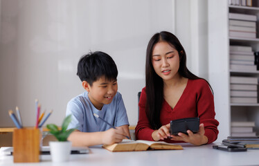 Asian teacher helping student with math homework using calculator