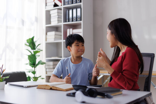 Asian teacher helping student with homework in modern classroom