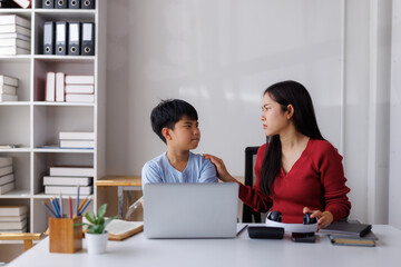 Asian mother scolding son while homeschooling him at home office desk