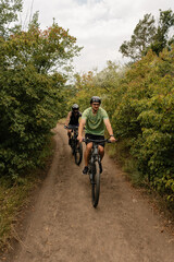 Two individuals cycling together through a lush forest trail, enjoying outdoor activity.