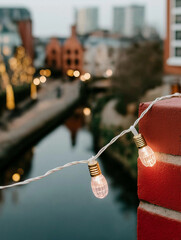 String of light bulbs hanging from a red brick wall. the string is strung across the wall, with the light bulbs facing towards the right side of the image.