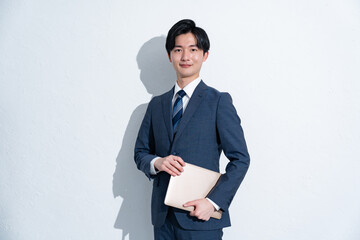 パソコンを持つスーツを着た若い日本人男性