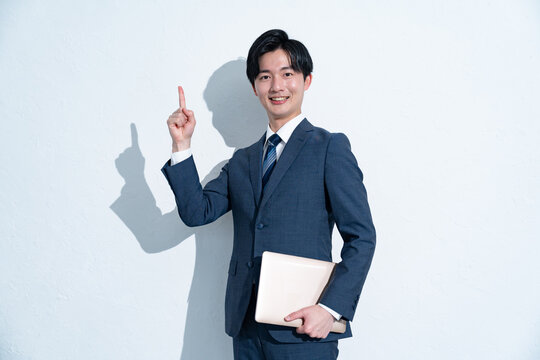 指差しをするスーツを着た若い日本人男性