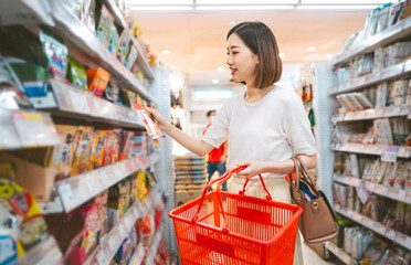 Asian woman consumer choosing food or seasoning product at supermarket store