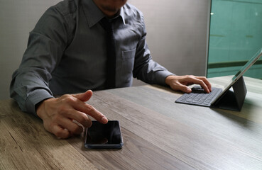 Businessman using smartphone and digital tablet in modern office