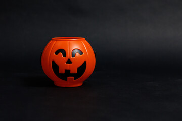 Photo decoration props orange plastic pumpkin jack o lantern bucket on black dark background for Halloween concept, happy funny ghost carnival holiday festival celebration, trick or treat, close up.